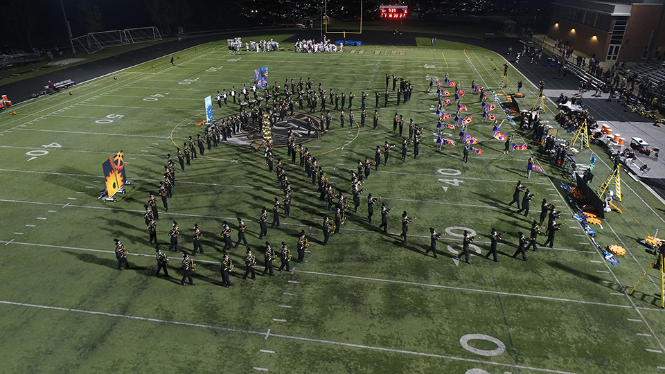 The marching band performs their theme of “Evolution of the Machine” at a football game.