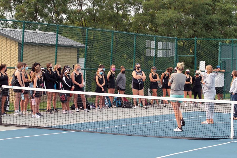 Members of the girls tennis team talk with their coaches before their match begins.