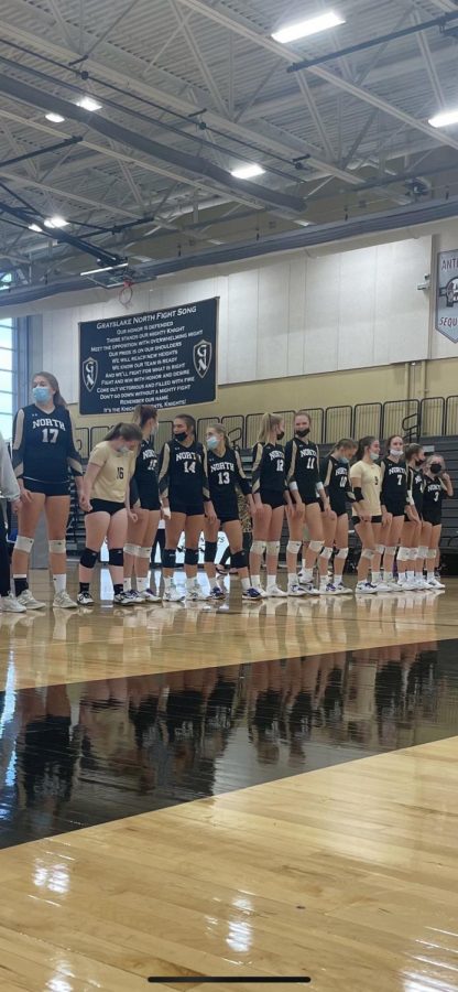 The volleyball team lines up for the National Anthem before the game.
