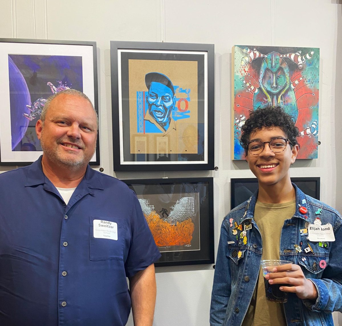 Art+teacher+Randy+Sweitzer+and+junior+Elijah+Bond+display+their+artwork+at+the+Illinois+Educator+Art+Exhibition.