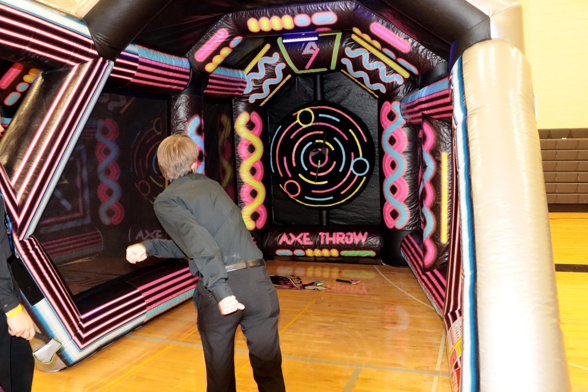 Student participates in the axe throwing inflatable at the Snowcoming Dance.